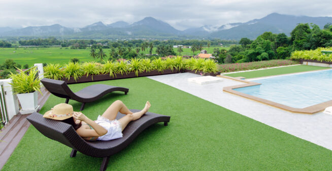 Woman relaxing in infinity swimming pool looking at mountain view