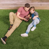 father with ball and little son laying on the grass at backyard, dad and son playing father with ball and little son laying on the grass at backyard, dad and son playing